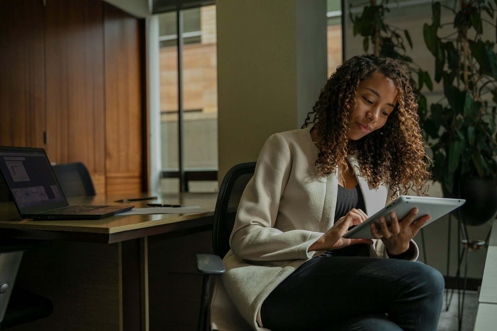 Professional woman with curly hair looking at her tablet